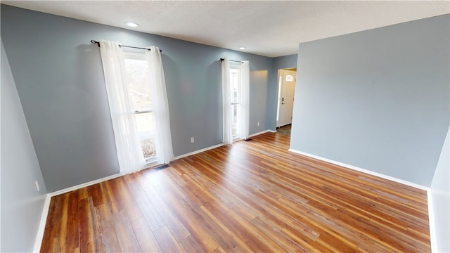 spare room featuring a textured ceiling, recessed lighting, wood finished floors, visible vents, and baseboards