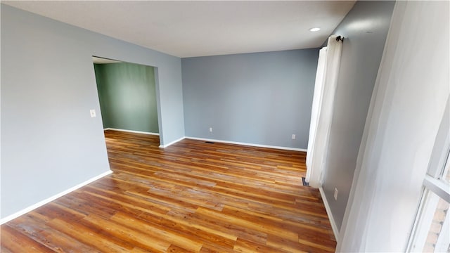 spare room with wood finished floors, visible vents, and baseboards