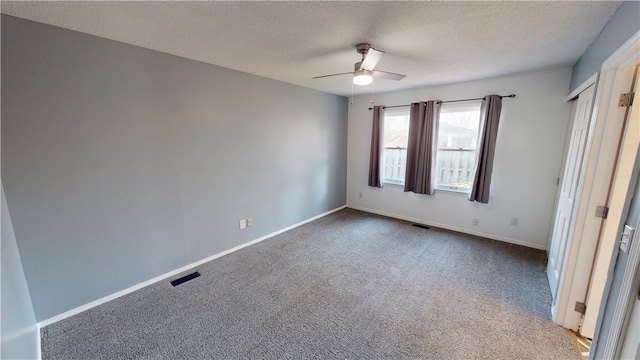 unfurnished bedroom featuring visible vents, dark carpet, ceiling fan, a textured ceiling, and baseboards