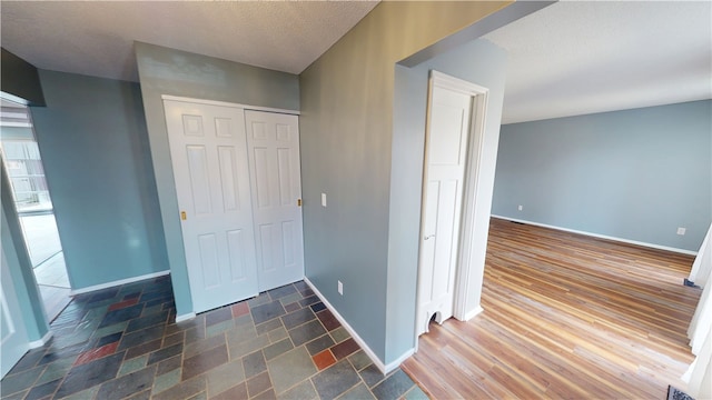 entrance foyer featuring dark wood-type flooring, a textured ceiling, and baseboards