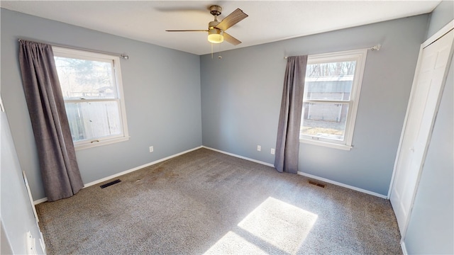 unfurnished bedroom featuring carpet, visible vents, and multiple windows