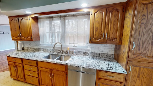 kitchen featuring a sink, light stone countertops, brown cabinets, and dishwasher