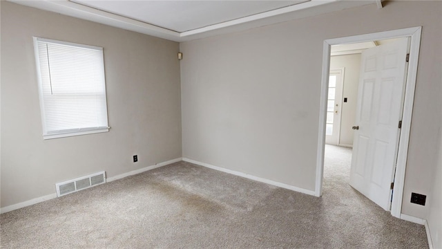 spare room featuring plenty of natural light and light colored carpet