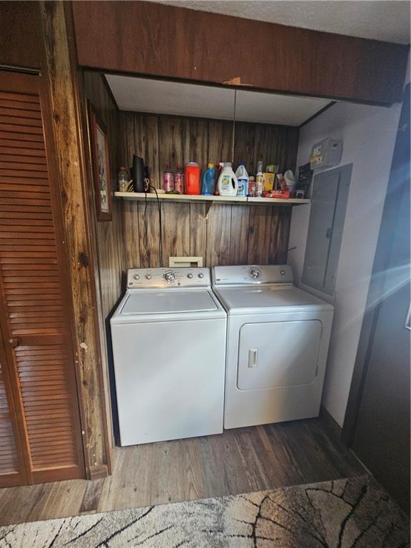 clothes washing area featuring washer and clothes dryer, wood walls, and wood-type flooring