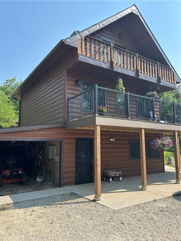 10760 E 1600th St, Cambridge, IL 61238 - view of front of home featuring a balcony, log veneer siding, dirt driveway, and an attached garage