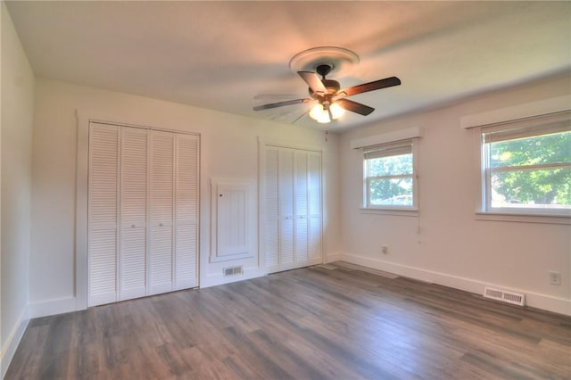 235 W Lawrence St, Illiopolis, IL 62539 - unfurnished bedroom featuring multiple closets, dark wood finished floors, and ceiling fan