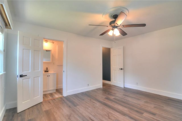 235 W Lawrence St, Illiopolis, IL 62539 - unfurnished bedroom featuring wood finished floors, ensuite bathroom, and a ceiling fan