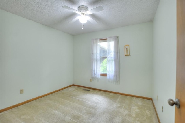 carpeted empty room featuring visible vents, a ceiling fan, a textured ceiling, and baseboards