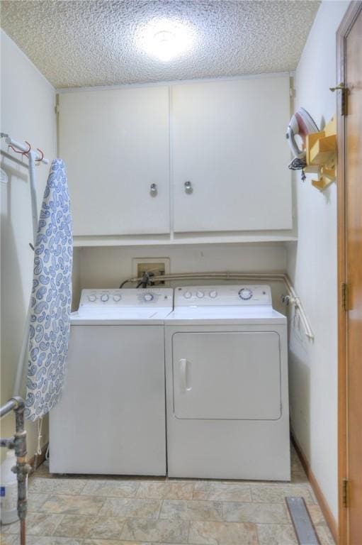 laundry room featuring a textured ceiling, cabinet space, and washer and dryer