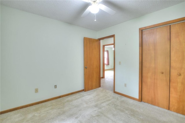 unfurnished bedroom with a closet, a ceiling fan, baseboards, a textured ceiling, and carpet flooring