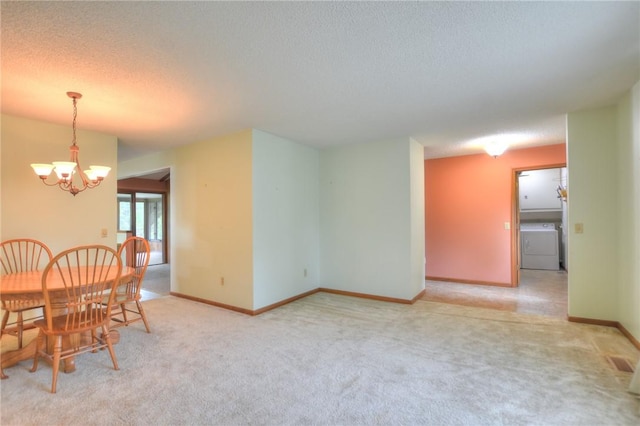 carpeted dining area with baseboards, a textured ceiling, washer / clothes dryer, and a chandelier