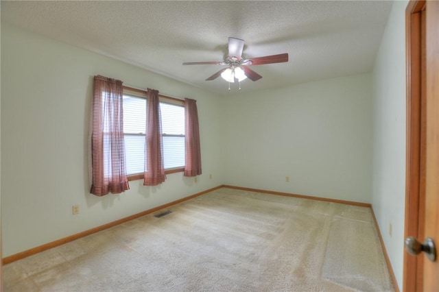 carpeted empty room featuring a ceiling fan, baseboards, visible vents, and a textured ceiling