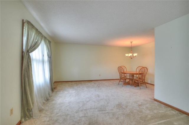 interior space with baseboards, a textured ceiling, carpet, and a chandelier