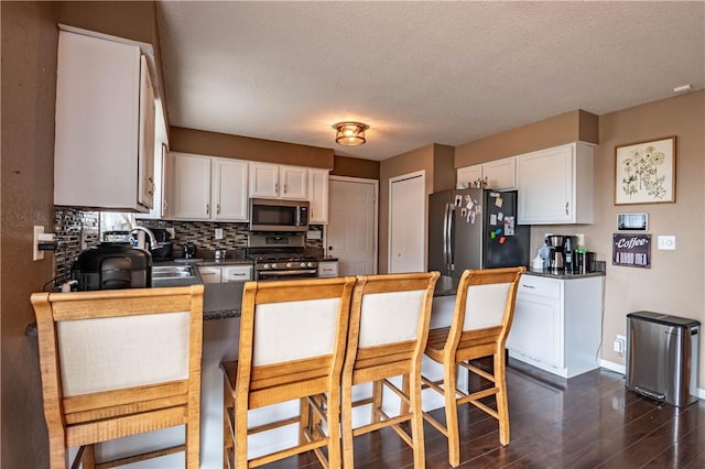 5334 Blue Mound Rd, Macon, IL 62544 - kitchen with stainless steel appliances, dark countertops, a peninsula, a textured ceiling, and dark wood-style flooring