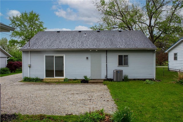 back of property featuring a yard, central AC unit, and a shingled roof