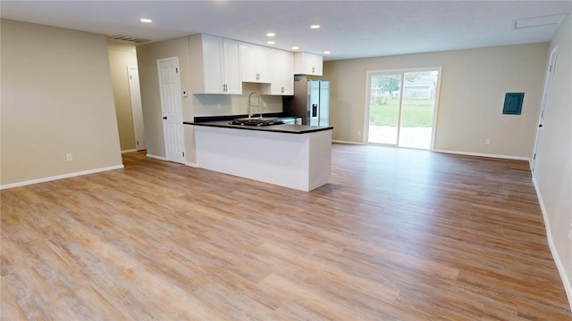 kitchen featuring visible vents, open floor plan, stainless steel refrigerator with ice dispenser, white cabinetry, and light wood-style flooring
