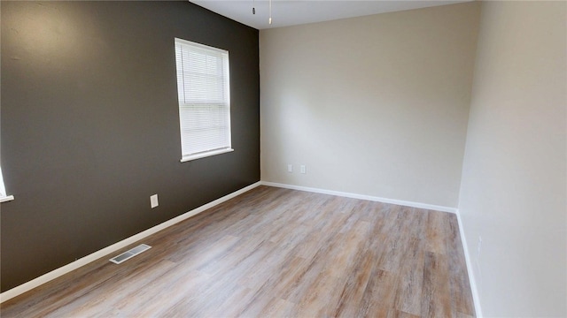 spare room featuring baseboards, light wood-style flooring, and visible vents