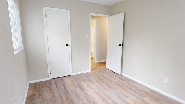 unfurnished bedroom with baseboards and light wood-type flooring