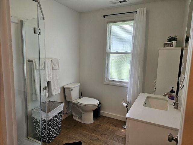full bath with plenty of natural light, toilet, wood finished floors, and a shower stall