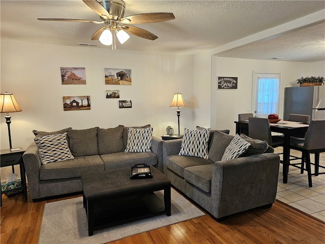 living room featuring a ceiling fan, wood finished floors, and a textured ceiling
