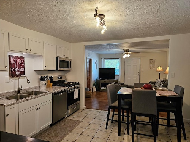 kitchen featuring a sink, stainless steel appliances, light tile patterned floors, white cabinets, and ceiling fan