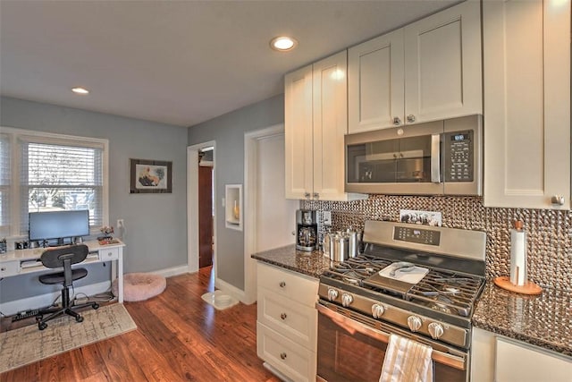 kitchen with tasteful backsplash, dark stone countertops, appliances with stainless steel finishes, dark hardwood / wood-style flooring, and white cabinets