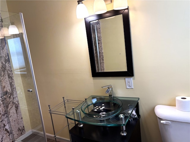 bathroom with tiled shower, vanity, and toilet