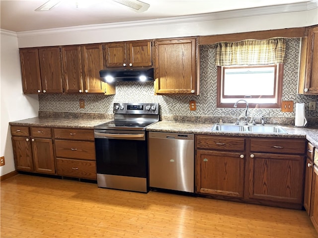 kitchen with under cabinet range hood, backsplash, a sink, light wood-type flooring, and appliances with stainless steel finishes