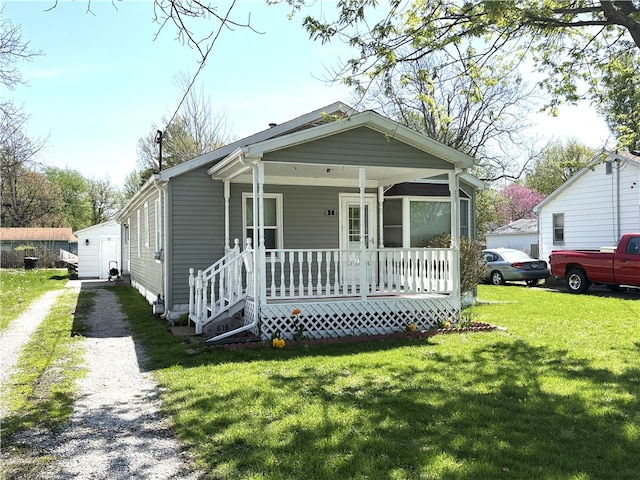 shotgun-style home with driveway, covered porch, and a front yard