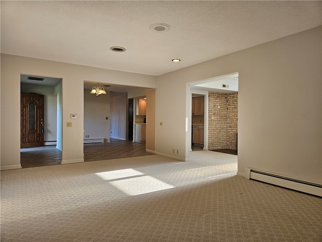 empty room with carpet, a textured ceiling, baseboard heating, and a notable chandelier