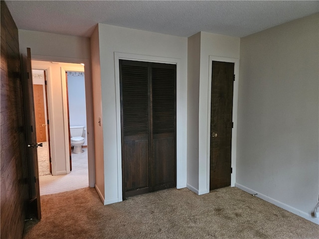 unfurnished bedroom with light colored carpet, a textured ceiling, and a closet