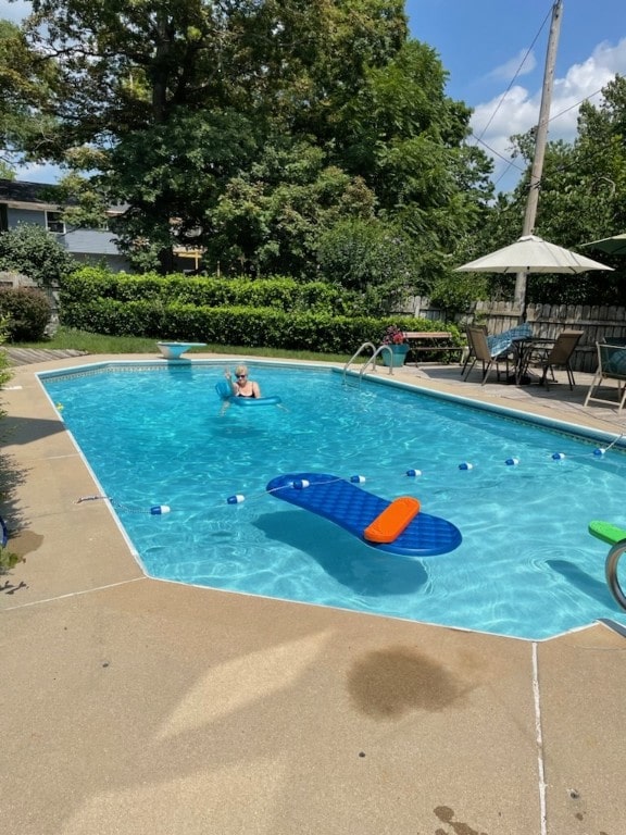 view of pool with a diving board and a patio area