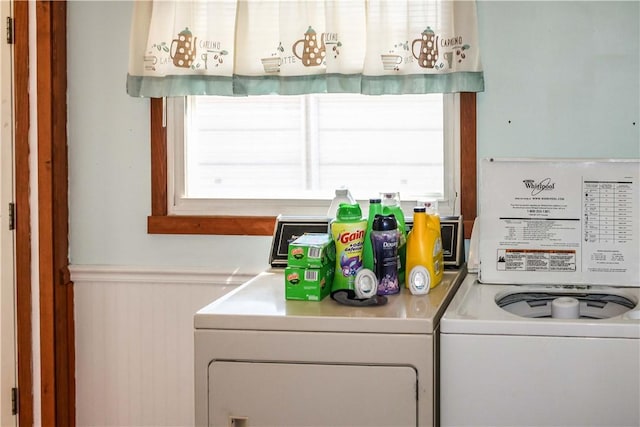 clothes washing area featuring laundry area, plenty of natural light, a wainscoted wall, and washer and clothes dryer