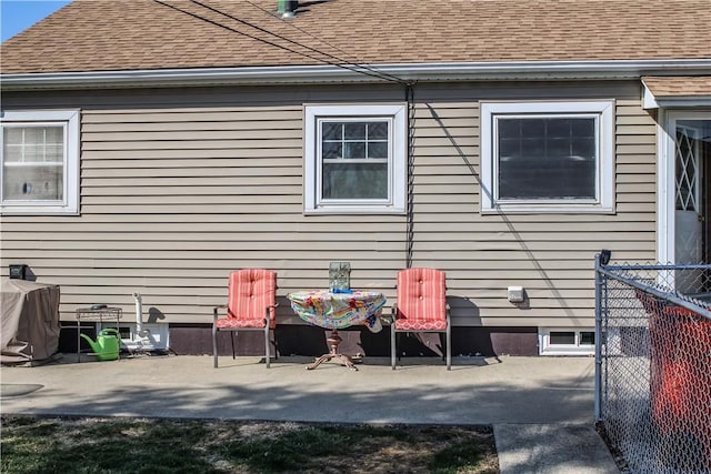 exterior space featuring a patio area, roof with shingles, and fence