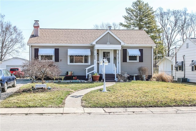 bungalow-style house with entry steps, a front lawn, roof with shingles, and a chimney