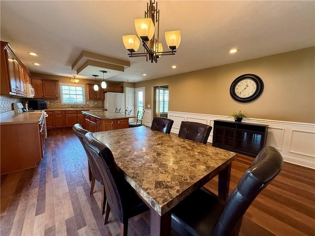 dining space featuring a notable chandelier, a decorative wall, dark wood-style floors, recessed lighting, and a wainscoted wall