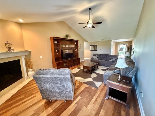 living area with wood finished floors, a fireplace, a ceiling fan, and lofted ceiling