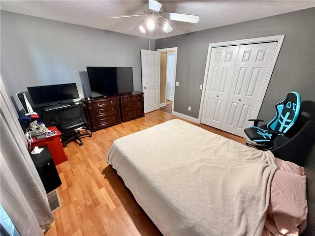 bedroom featuring light wood-style floors, a closet, a ceiling fan, visible vents, and baseboards