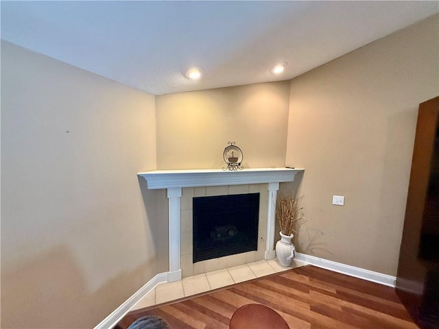 interior details featuring a tiled fireplace, baseboards, recessed lighting, and wood finished floors