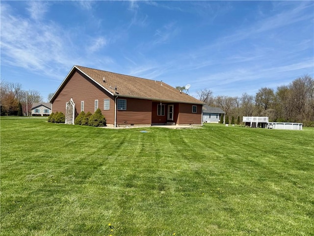 back of property featuring crawl space, a shingled roof, a patio, and a lawn