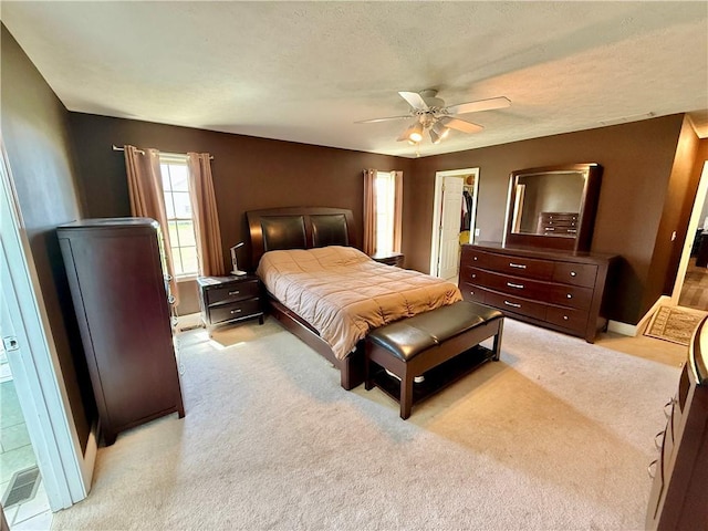 bedroom with a walk in closet, a closet, a ceiling fan, and light carpet
