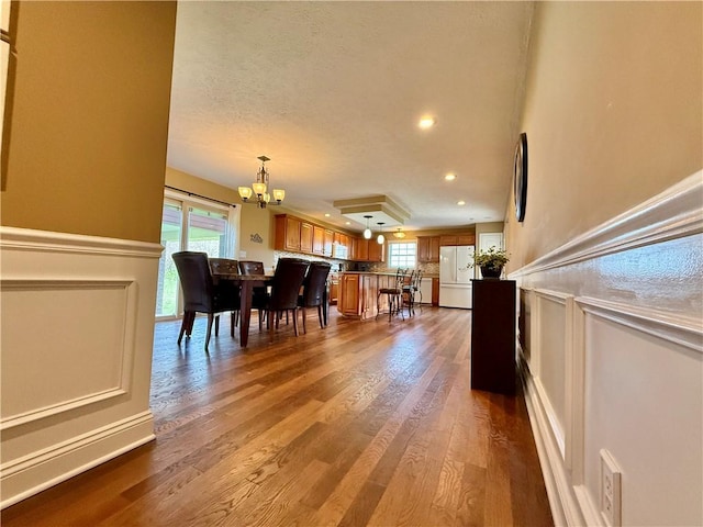 dining area with dark wood-type flooring, an inviting chandelier, and a healthy amount of sunlight