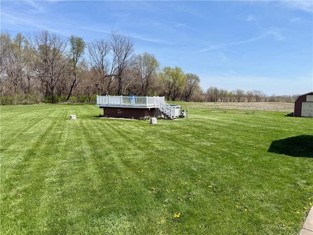 view of yard featuring a storage shed, an outbuilding, and a wooden deck