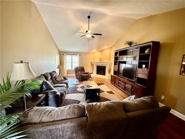 living room with baseboards, vaulted ceiling, a ceiling fan, and wood finished floors