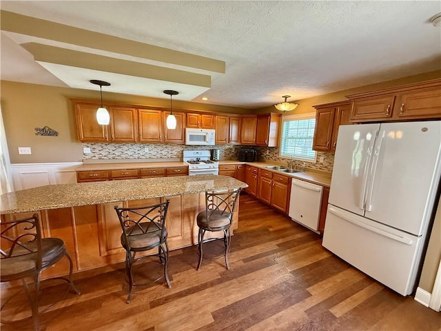 kitchen featuring a sink, dark wood-style flooring, white appliances, a textured ceiling, and brown cabinets