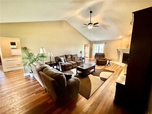 living area with baseboards, a fireplace, a ceiling fan, lofted ceiling, and wood finished floors