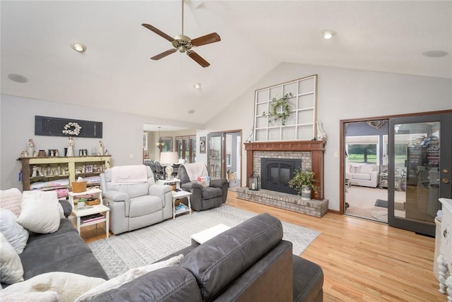 living room with a fireplace, light hardwood / wood-style floors, high vaulted ceiling, and ceiling fan