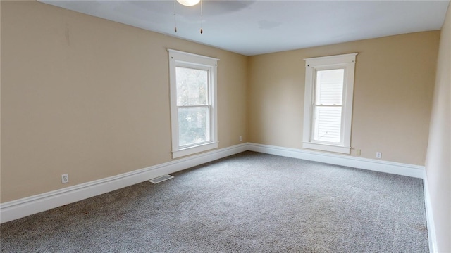 carpeted spare room featuring ceiling fan and a healthy amount of sunlight