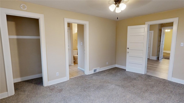 unfurnished bedroom featuring light carpet, a closet, ceiling fan, and ensuite bathroom