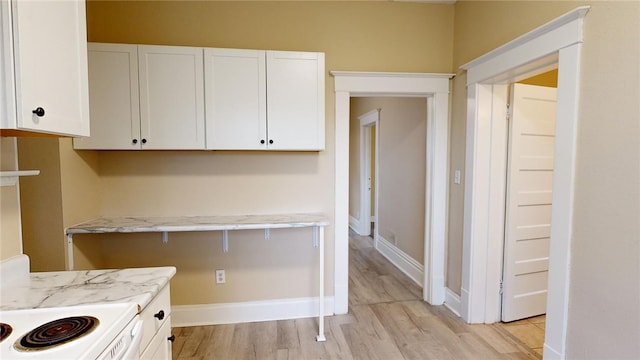 kitchen featuring white cabinetry, light hardwood / wood-style flooring, light stone countertops, and white stove